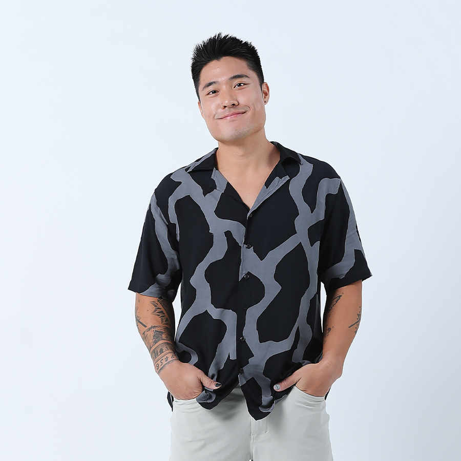 a male model posing in front of a neutral background in a batik cuban shirt in the pattern jet chain