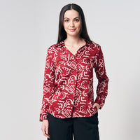 A woman striking a pose in a Crimson Diwanie batik shirt, elegantly showcased against a clean white background, highlighting the vibrant pattern and stylish design