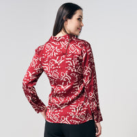 A woman gracefully showcasing the back of a batik shirt in the captivating Crimson Diwanie pattern against a neutral background, highlighting the intricate details of the design