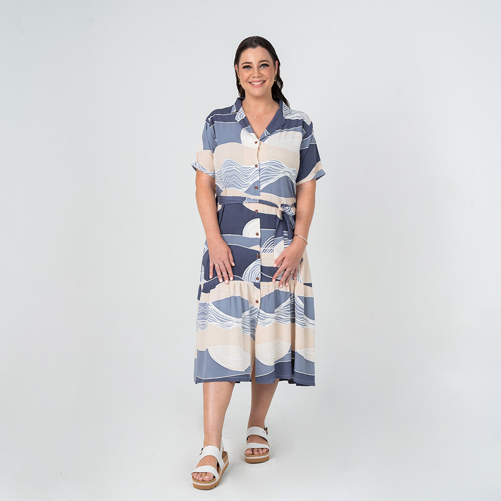 Front view of model wearing Batik Boutique’s Button-Up Dress in Lavender Bukit print, made from breathable cotton with a self-tie waist.