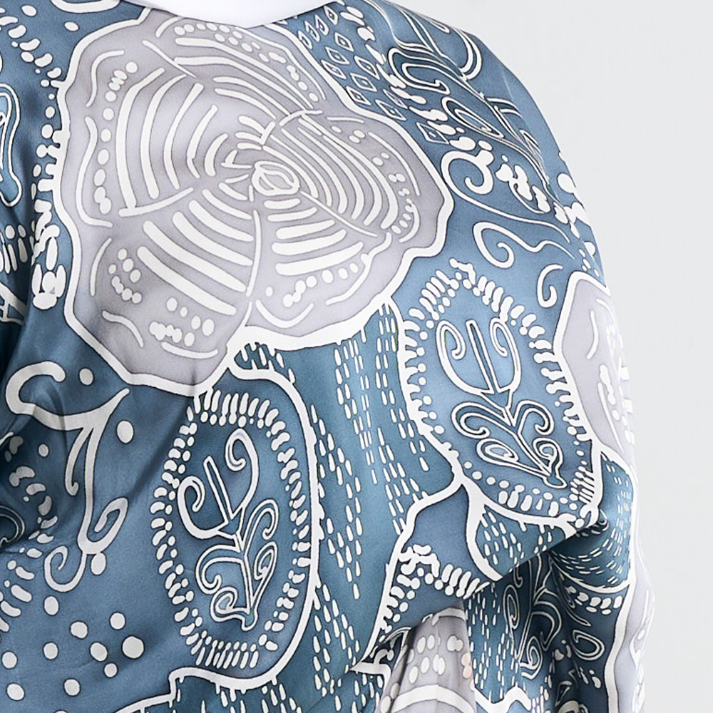 Close-up of the intricate floral batik pattern on the slate blue caftan