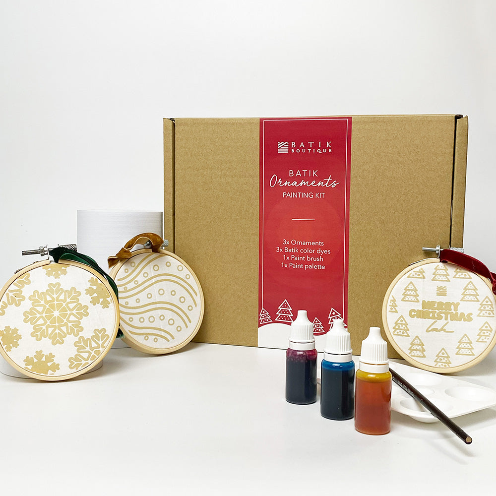 A lifestyle photo of Batik Ornaments Painting in Set of 3. The outsiode of the box showcasing 3 handmade batik ornaments that can be paint 