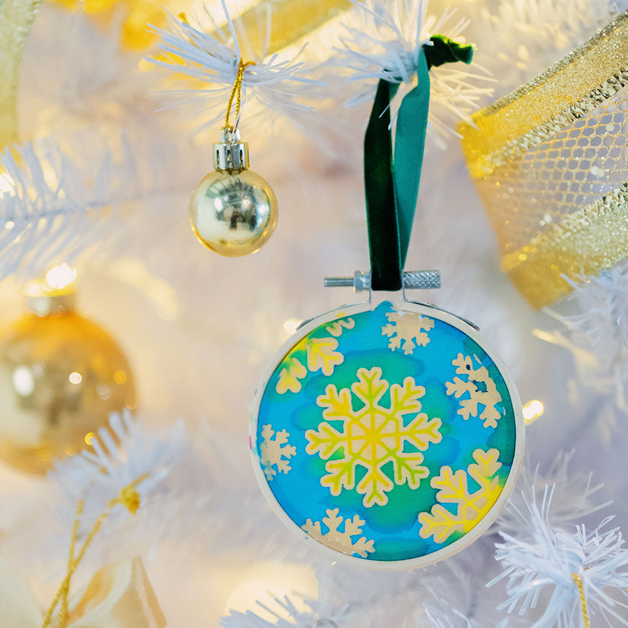 A lifestyle photo of batik painting ornaments in "Snowflakes" Pattern. With white christmas tree as background
