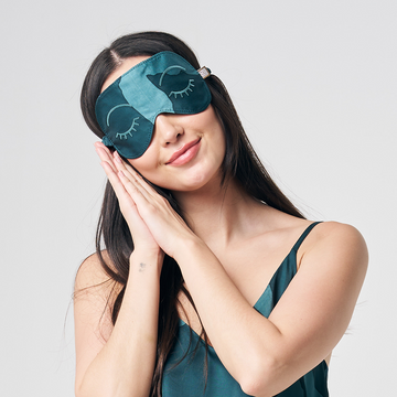 a photo of a woman in front of a neutral background while wearing a batik eye mask and batik camisole