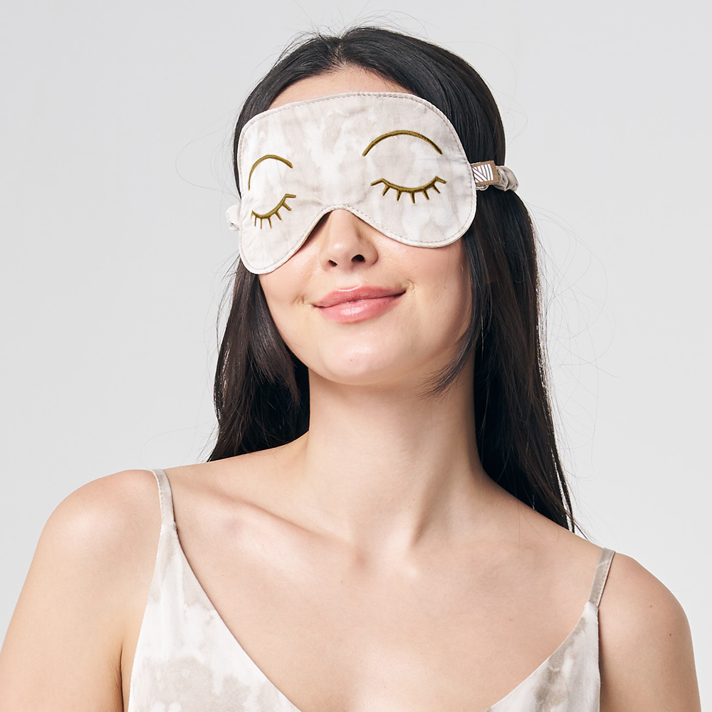 a woman posing with a shibori eye mask in the pattern mangosteen against a neutral background