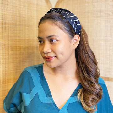 A woman is wearing batik headband in Black Fern pattern made by remanant batik fabric for more sustainable approach