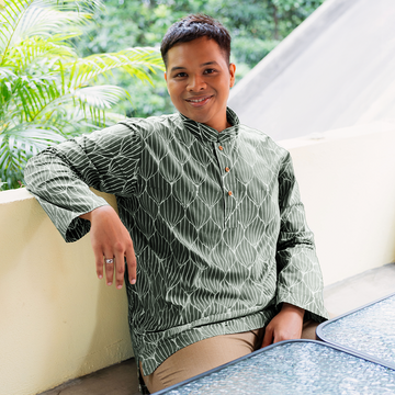 a male model sitting while wearing a batik shirt in the pattern olive bawang