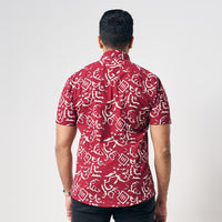 A man is wearing handcrafted batik short sleeve shirt in Crimson Diwanie, white and red color shirt. While posing in front of white background