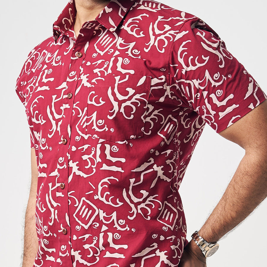 A closeup photo showing button on cotton short sleeve shirt in Crimson Diwanie, which is red color. Shirt is handcrafted by skilled artisans