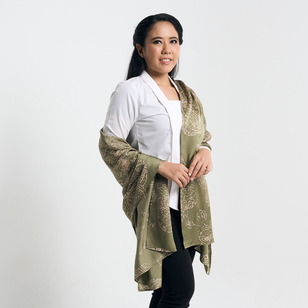 Model draping a moss green batik scarf over a white outfit