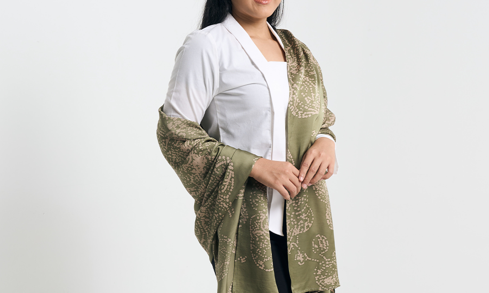 Model draping a moss green batik scarf over a white outfit