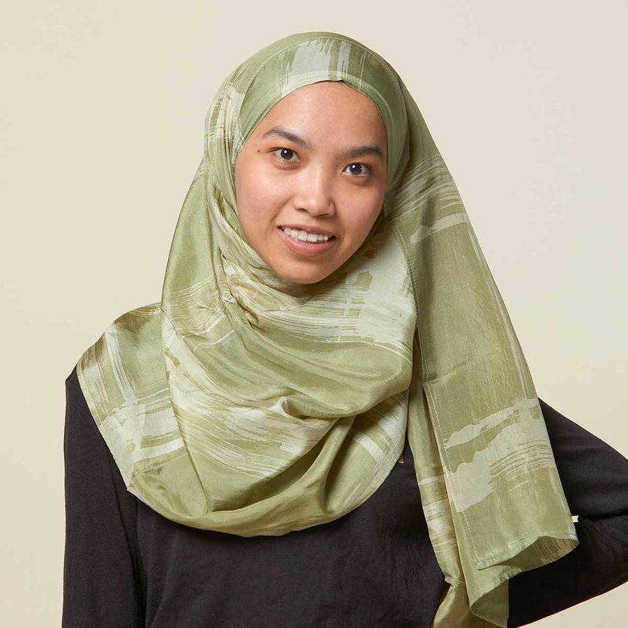 Muslim woman wearing batik tudung scarf in olive cotton silk.