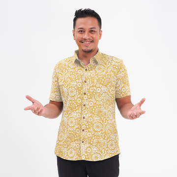 a male model posing in front of a white background while wearing an authentic batik shirt in the pattern mustard ukir