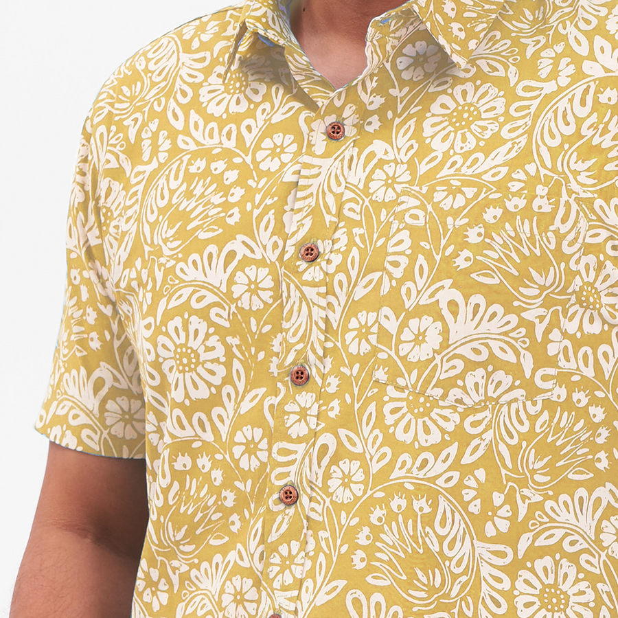a closeup shot of a batik shirt in the pattern mustard ukir against a neutral background