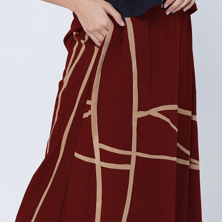 a close up photo of model wearing crimson color batik skirt in crimson brush pattern