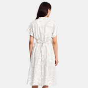 Woman wearing grey printed batik dress facing the back, showing the features of the back of the dress