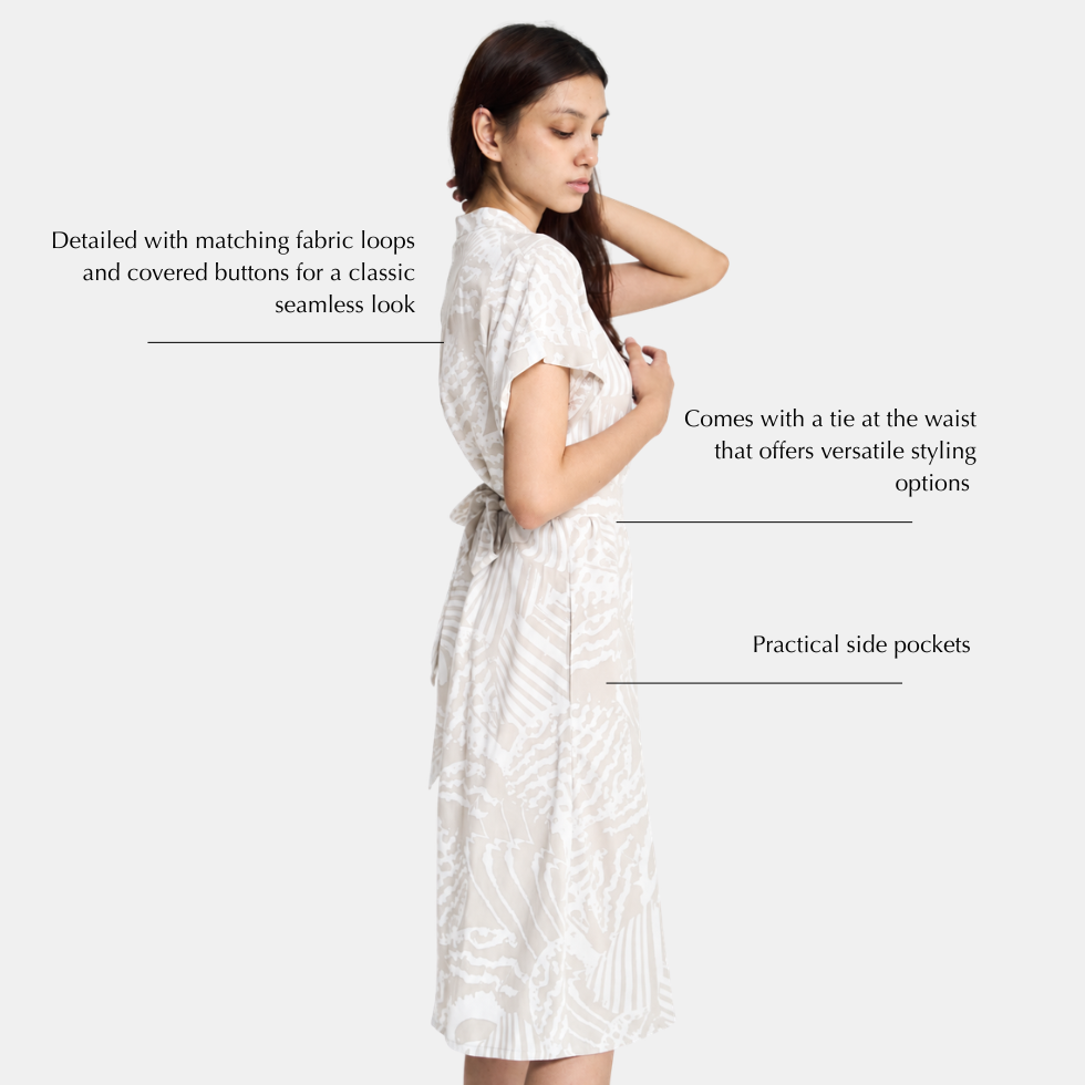 A woman modeling a white patterned short-sleeve dress with a tie waist, shown against a light gray background with text callouts describing features like matching fabric loops, a tie at the waist, and side pockets.