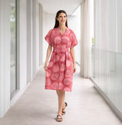 Woman wearing a pink dress with a pattern in a modern indoor setting
