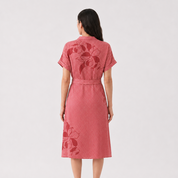 Woman wearing a batik pink dress with floral patterns on a white background