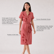 Woman wearing a coral pink batik dress with floral patterns on a light gray background