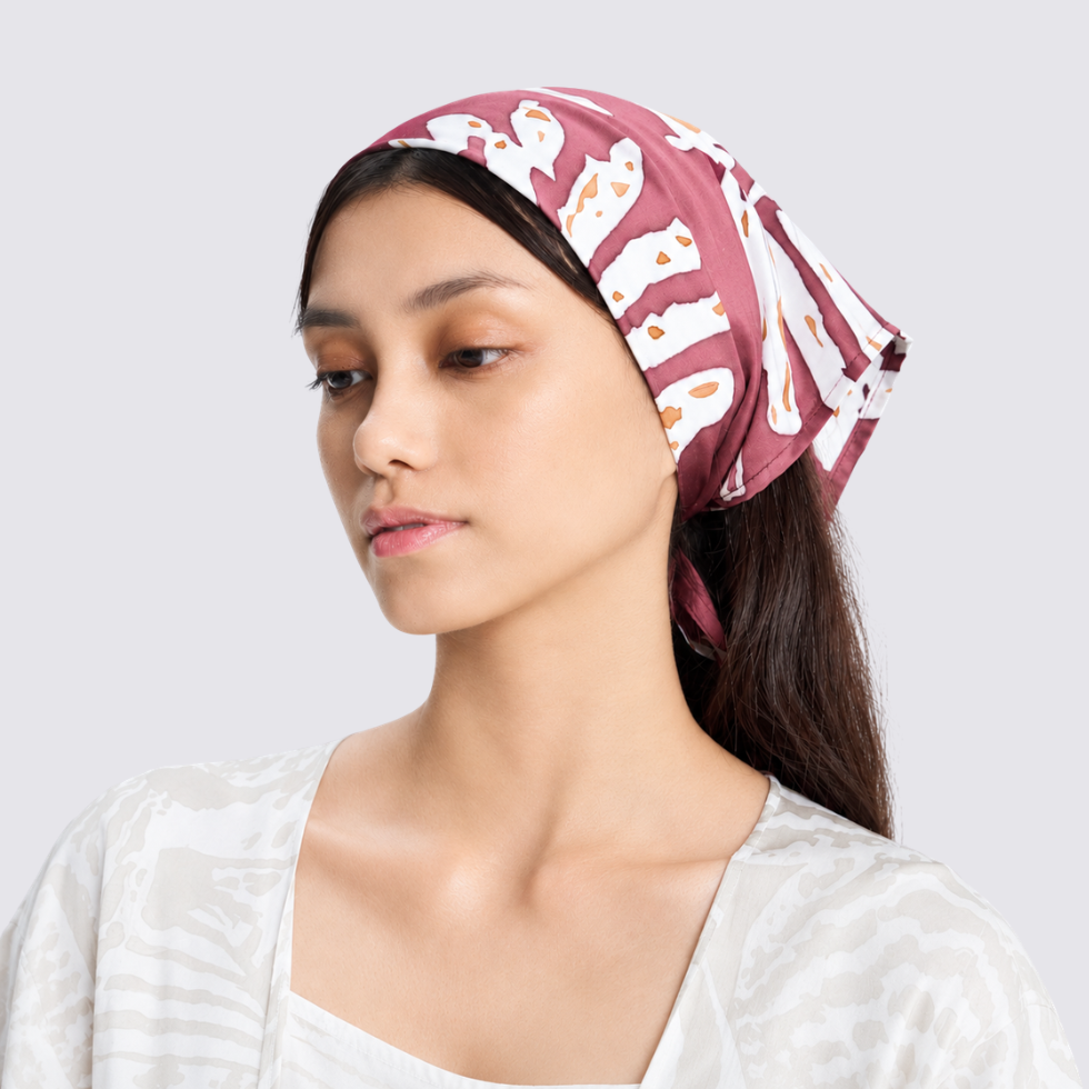 Girl wearing maroon batik bandana tied at the head tilting her head away from the camera