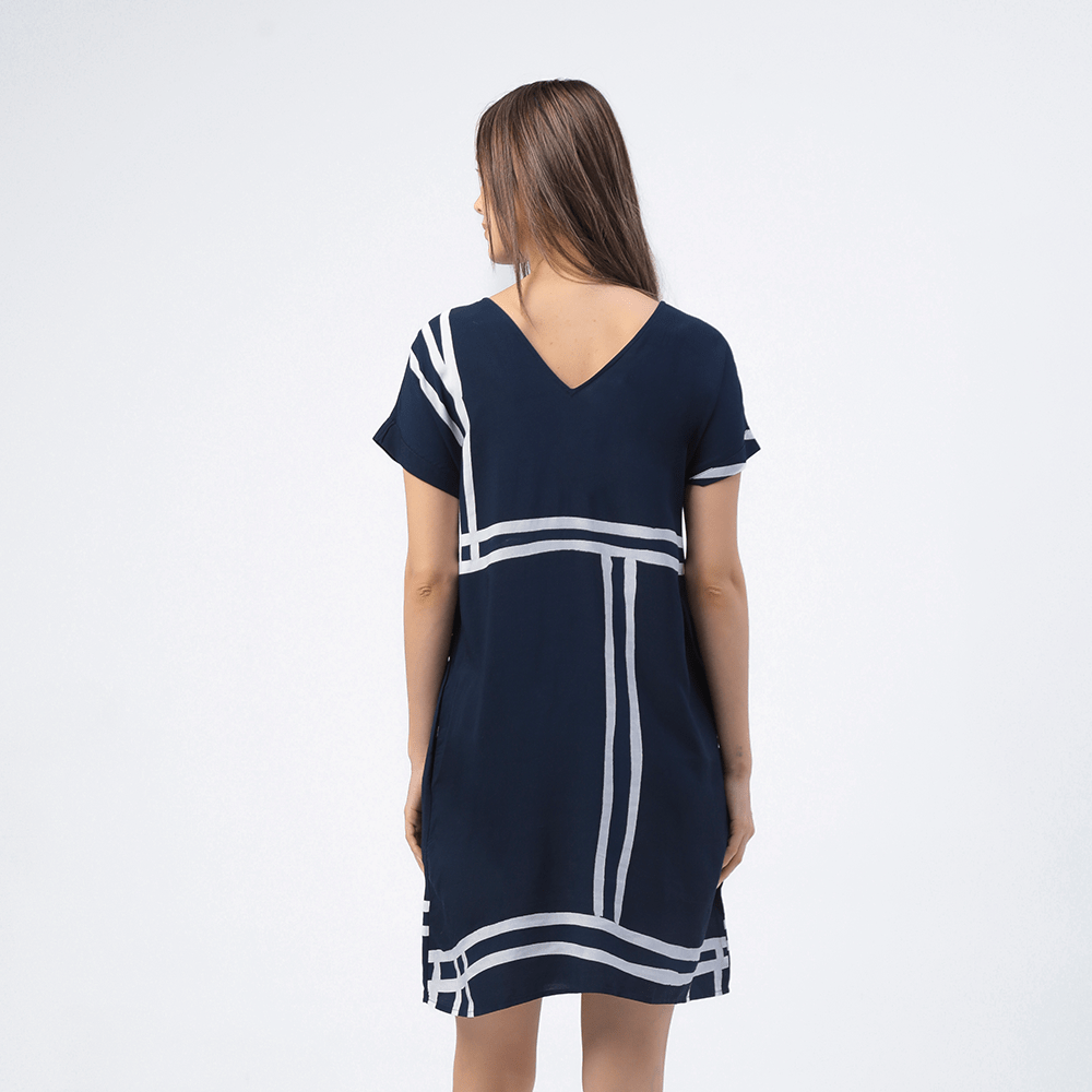 the back of a woman to showcase the design on the back of a batik dress against a white background in a reversible neckline