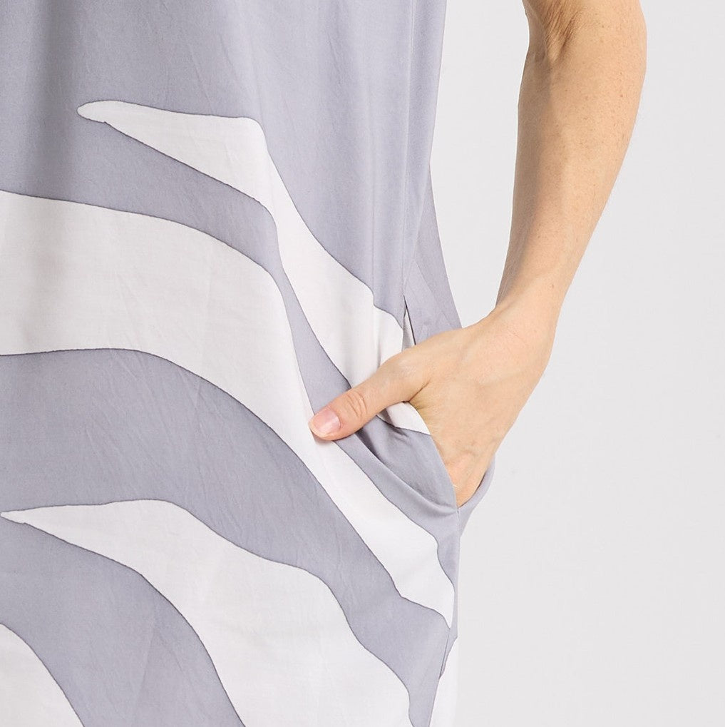Hand holding gray and white patterned fabric against a plain background