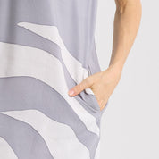 Hand holding gray and white patterned fabric against a plain background