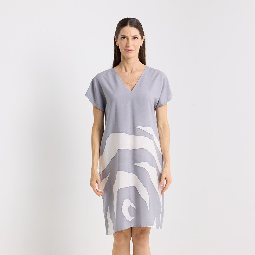 Woman wearing a gray dress with white abstract patterns on a light gray background