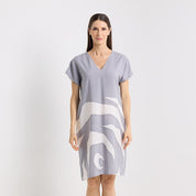 Woman wearing a gray dress with white abstract patterns on a light gray background