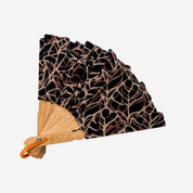 A folding hand fan with a black and brown abstract patterned fabric, a natural wood handle, and an orange plastic grip, shown on a plain white background.