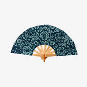 A folding hand fan with a dark teal and light blue floral pattern on the fabric cover, featuring a natural bamboo handle and wooden ribs, shown against a plain light gray background.