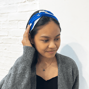 Woman wearing a blue and white patterned headband against a light background