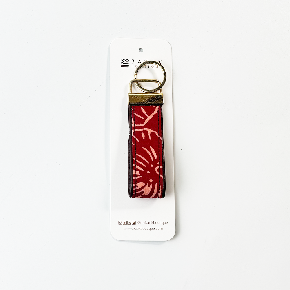 Red floral patterned keychain on a white card with brand logo