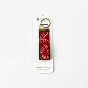 Red floral patterned keychain on a white card with brand logo