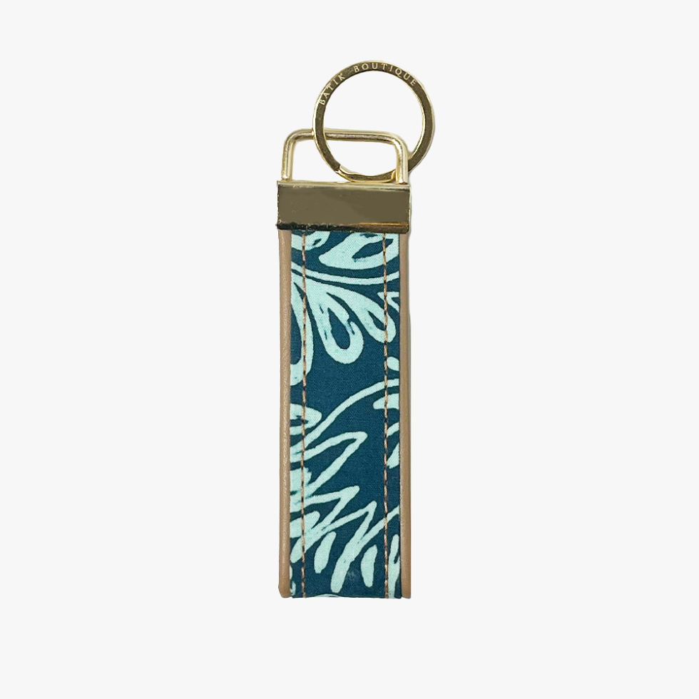 A rectangular leather keychain strap featuring a teal and light blue floral batik pattern, finished with a brass key ring and metal hardware.