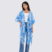 Woman wearing a blue and white patterned kimono over a white top and jeans on a light gray background