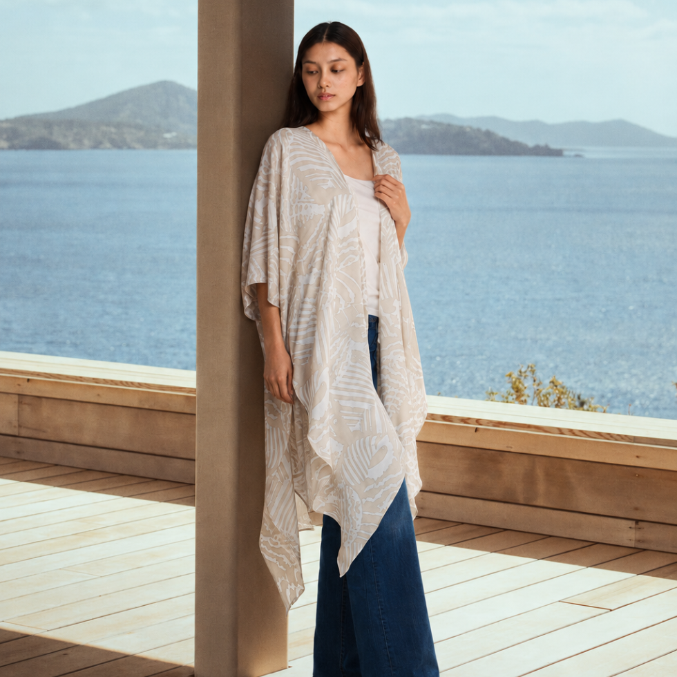 Woman wearing gray printed batik kimono, posing at a wooden viewpoint by the beach