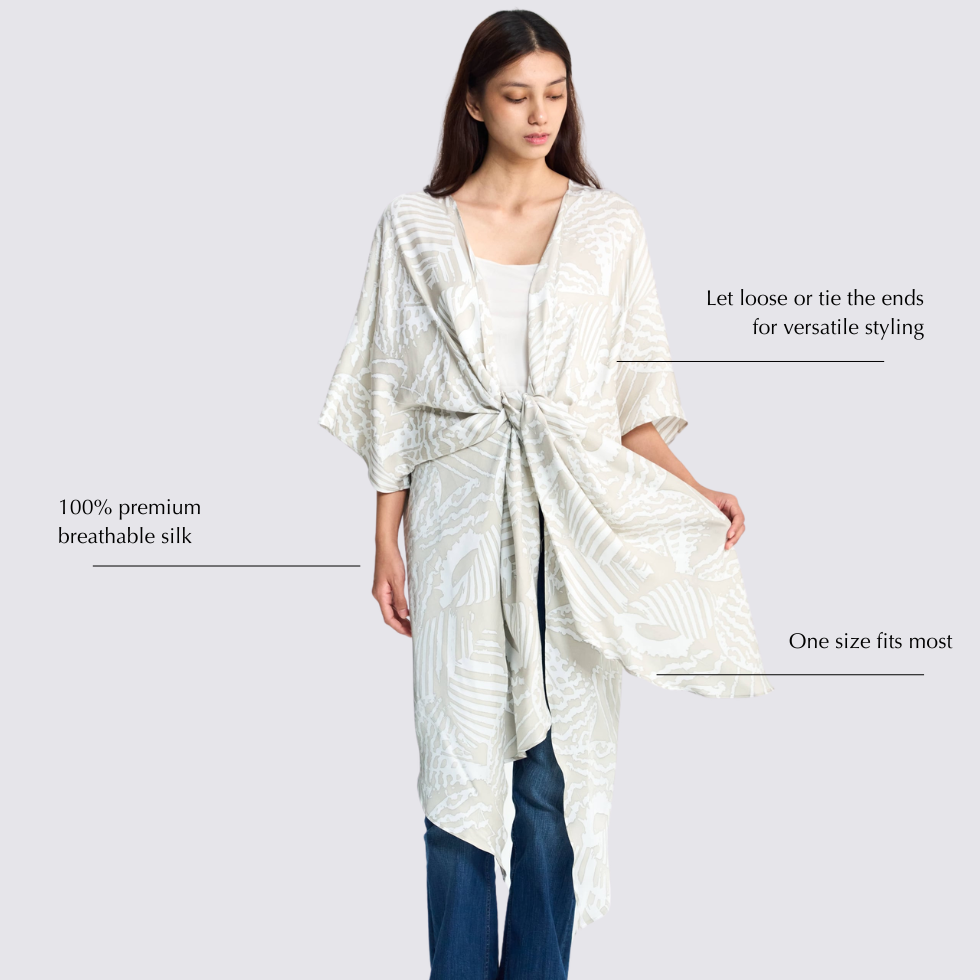 Girl wearing grey print batik kimono, with it tied at the front, looking down with informational details at the side
