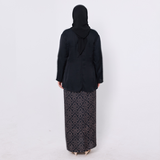Person wearing a black outfit with a patterned skirt on a white background