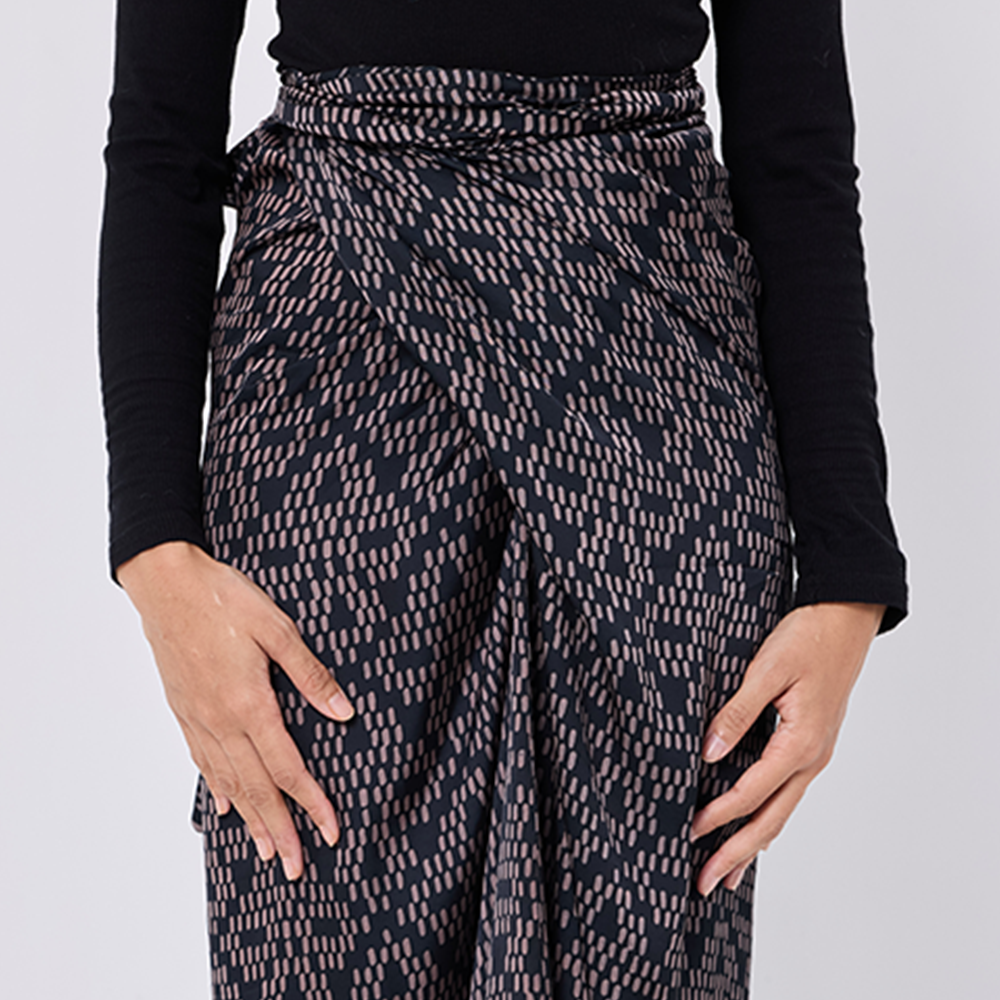 Person wearing a patterned skirt with a plain background