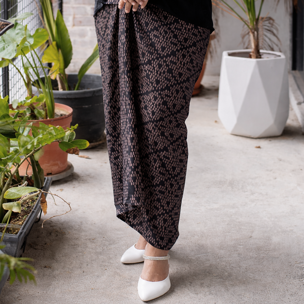 Person wearing patterned pants standing in a room with plants
