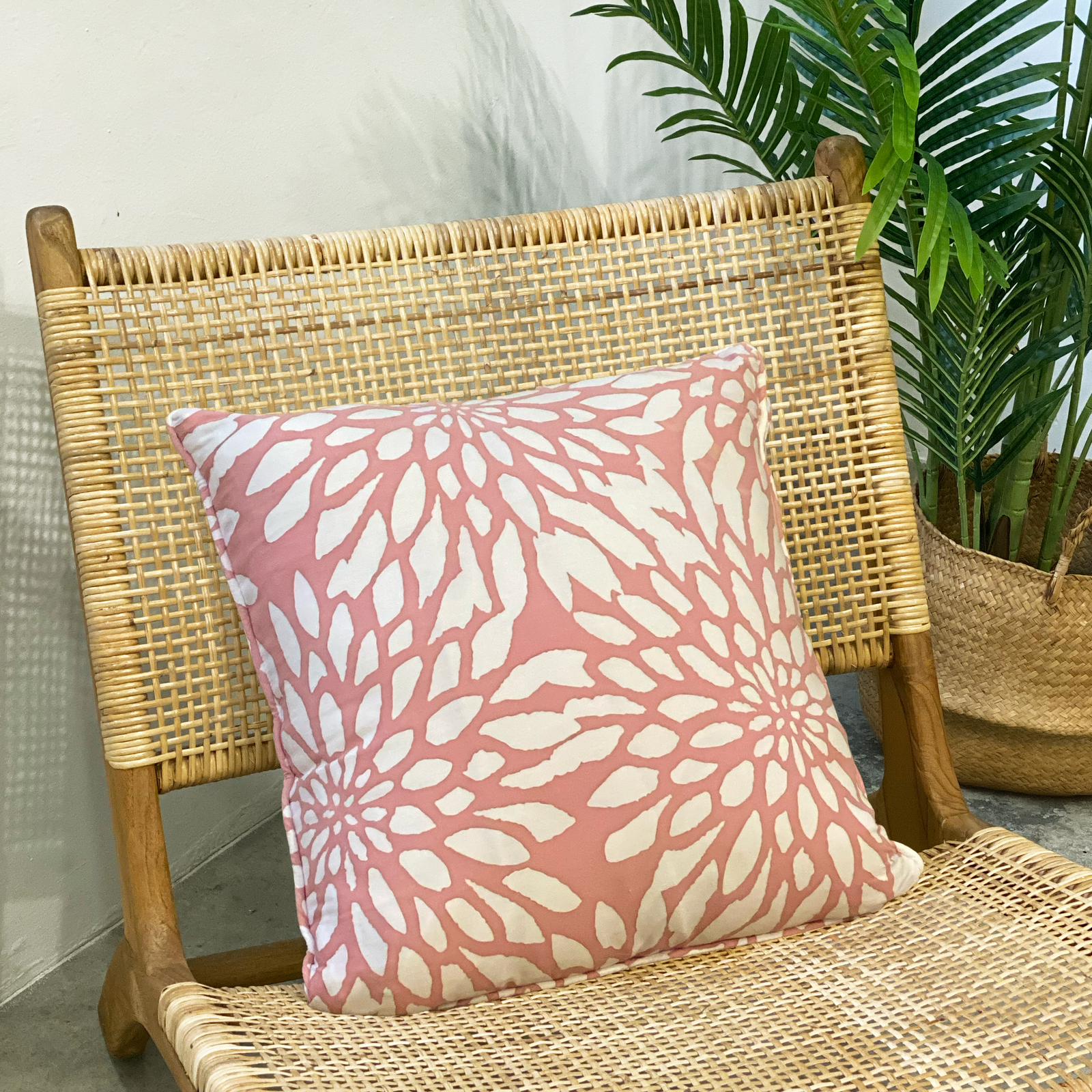 a batik pillow against a rattan chair in the pattern coral bunga