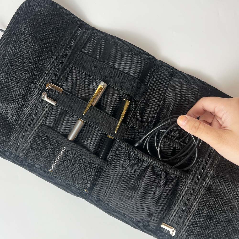 Black tool roll with compartments containing tools, held by a hand on a white background