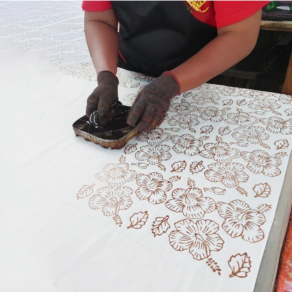 Person using a stamp with floral patterns on a white surface