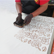 Person using a stamp with floral patterns on a white surface