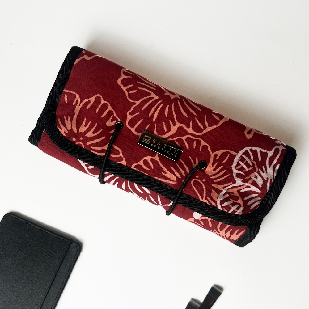 Red floral-patterned roll-up pouch with black trim on a white background