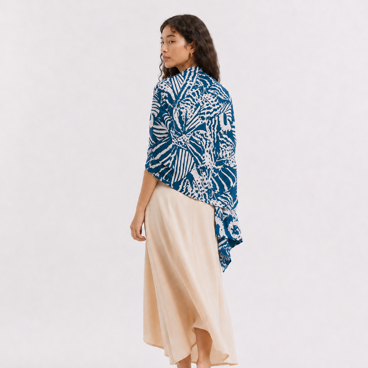 Woman wearing a patterned blue scarf on a white background
