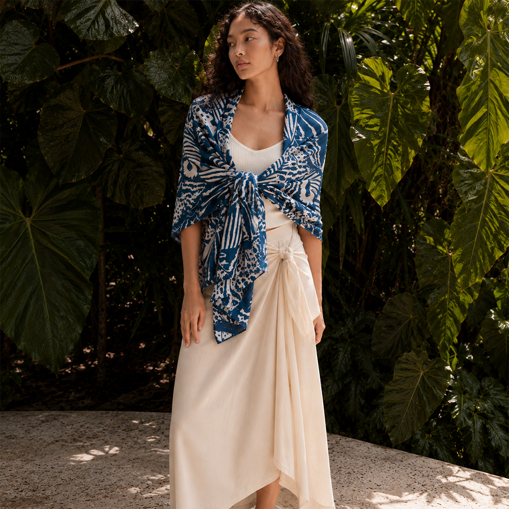 Woman wearing a patterned scarf standing outdoors with trees