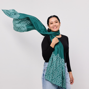 Woman wearing a green scarf with a white pattern against a plain background